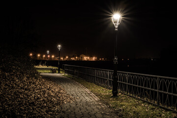 Fototapeta alejka nad brzegiem rzeki oświetlona latarniami obraz