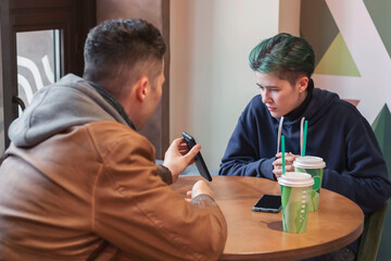 A guy and a girl are sitting in a cafe and using smartphones. Communication, technology, internet.