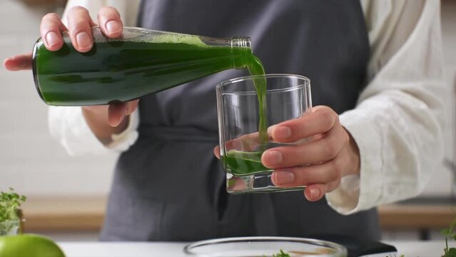 The cook pours fresh juice into a glass. Close-up pouring green juice into a glass. Detox as a way of life. Healthy food. Preparation of organic fresh diet drink
