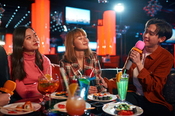 Group of friends having fun and singing songs at karaoke club