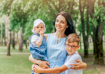 Fototapeta premium Mom with two little children walking outdoor, summer weather