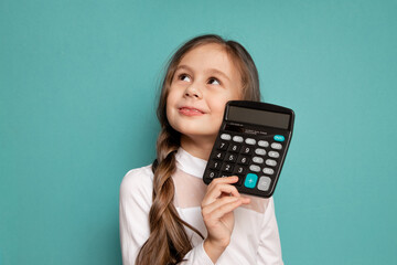 Portrait of a serious little girl holding a calculator on a blue background.