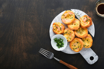 Delicious egg muffins with green onions, bacon, cheese and tomatoes on wooden board on old wooden rustic background. Healthy high protein and low carb breakfast. Homemade food.