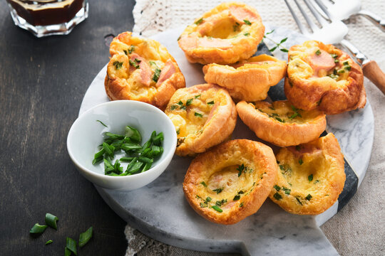 Delicious egg muffins with green onions, bacon, cheese and tomatoes on wooden board on old wooden rustic background. Healthy high protein and low carb breakfast. Homemade food.