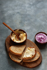homemade loaf of bread and butter with jam on grey concrete background. Natural light with soft shadows