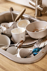 Pile of unwashed, dirty dishes in the sink. Mess in the kitchen. Dirty kitchenware, plates and mugs. Chaos at home. Laziness. Cluttered apartment. Messy cutlery and dishware.