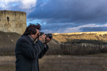 a young man - a photographer took aim with a camera in the background of a large white rock on a sunny winter day