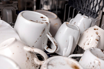 Unwashed, dirty dishes in dishwasher. Mess in the kitchen. Dirty kitchenware, plates and mugs....