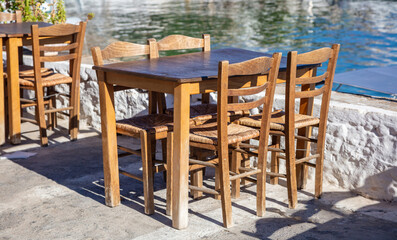 Fototapeta na wymiar Outdoor seaside tavern, fish and sea food taverna empty table and chair, summer sunny day. Greece