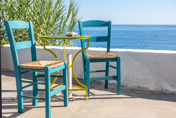 Outdoor seaside cafe, coffee and drink bar empty table and chair, summer sunny day. Greece