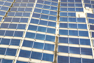 Obraz premium Aerial view of solar power plant with blue photovoltaic panels mounted of industrial building roof.