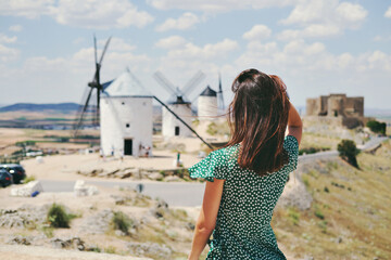 Rear view woman posing against windmills in Consuegra town. Spain - obrazy, fototapety, plakaty