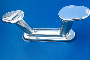 Stainless steel mooring bollard on the blue hull of the yacht.