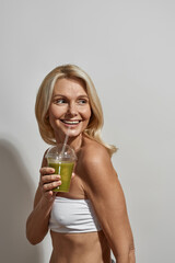 Smiling middle aged woman drink cocktail or juice