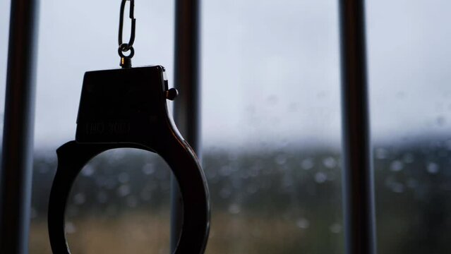 Handcuffs silhouette swing on prison bars