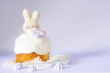 Easter cake and decorated with sugar icing and meringue and Easter decorative bunny on the background of color of year 2022Very Peri with copy space. Easter Orthodox sweet bread kulich. Easter card