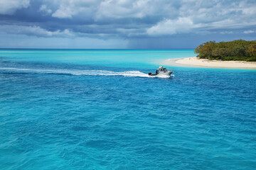 Boat going through the channel between Mouli and Ouvea Islands, Loyalty Islands, New Caledonia. - obrazy, fototapety, plakaty