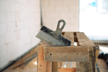 photograph of a construction trowel with a black handle on a construction site with a blurred background