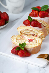 Sweet roll stuffed with strawberry and cream decorated with strawberries, powdered sugar and mint leaves