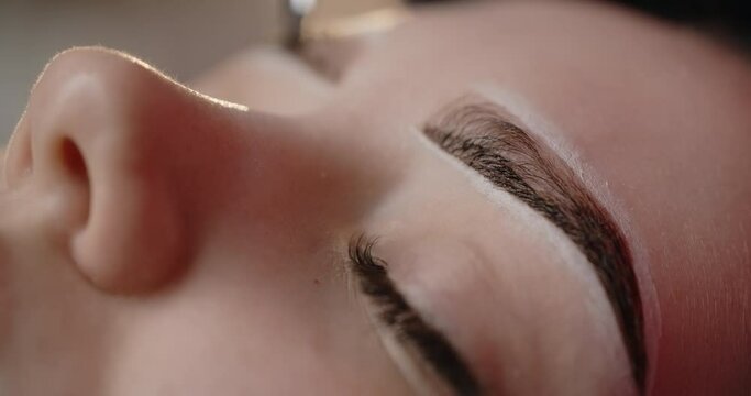 A beautician does henna eyebrow tinting for the young woman, cosmetological procedures and beautycare, 4k Prores 60p