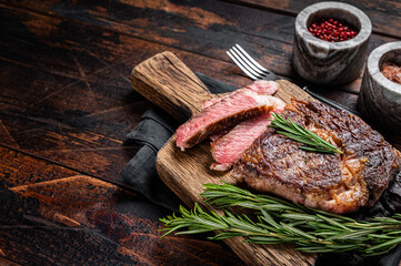 Sliced and Grilled rib eye steak, rib-eye beef marbled meat on a wooden board. Wooden background. top view. Copy space