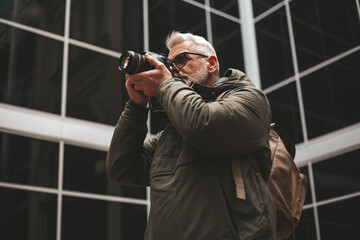 Mature man - photographer journalist with a camera in his hands. Travel and hobbies in retirement.