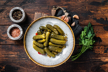 Plate with Pickled gherkins cucumbers on wooden board. Wooden background. Top view