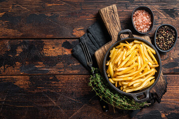 Skilet full of Potato french fries with salt. Wooden background. Top view. Copy space