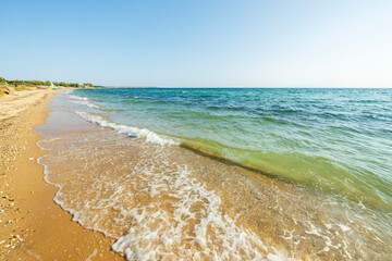 Beautiful view of shore line on bright summer day.  Sandy coast line and blue sea water merging to...