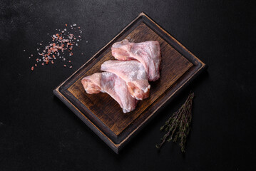 Chicken wings lie on a wooden board on a black background