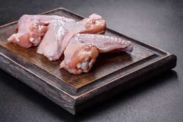 Chicken wings lie on a wooden board on a black background