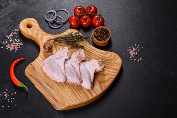 Chicken wings lie on a wooden board on a black background