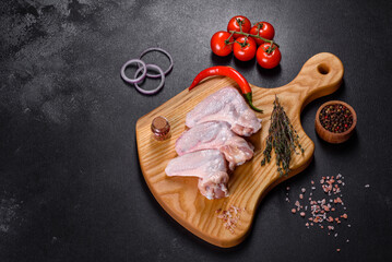 Chicken wings lie on a wooden board on a black background