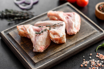 Chicken wings lie on a wooden board on a black background