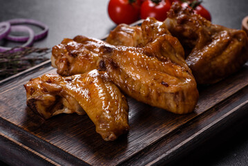 Baked chicken wings with vegetables and spices on a black background