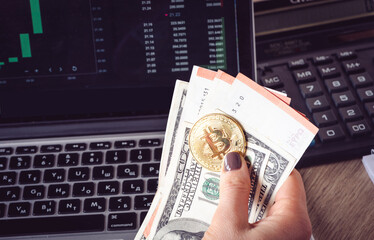 American dollars and bitcoin on the background of the screen with financial charts
