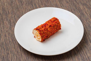 Healthy cheese rolled into a roll wrapped in spices..The cheese is on a white plate.