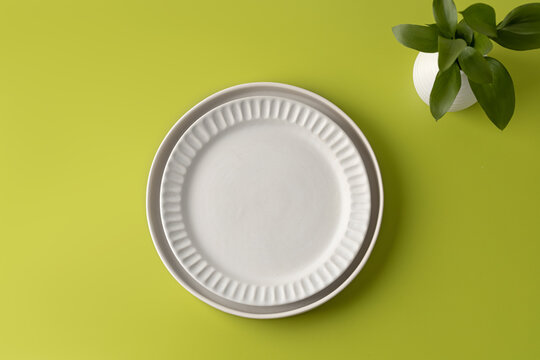 Plate. White round plate for food, mock up on light green background. Top view. Simple and minimalism.