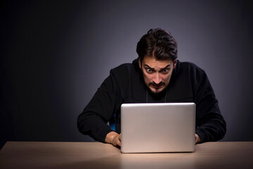 Young male hacker on grey background