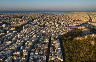 Sunrise, top view of the famous Athens, rectangular streets and a grid of buildings, quarters directed towards the sea, mountains on the horizon, Greece