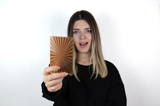 Young woman with casual clothes holding magical card and showing it to the camera. She is so happy and smiling. Photo taken is white isolated background.
