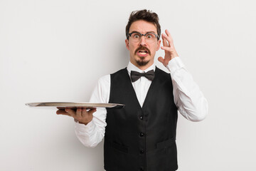 young handsome man screaming with hands up in the air. waiter and tray concept