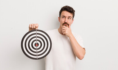 young handsome man thinking, feeling doubtful and confused. dart target concept