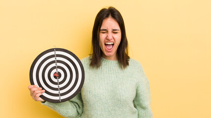 young hispanic woman shouting aggressively, looking very angry. darts target concept