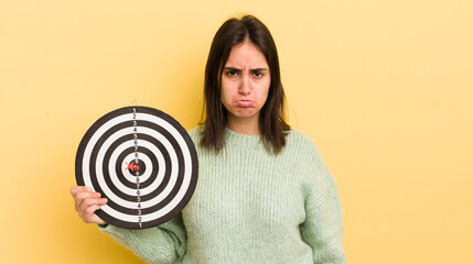 young hispanic woman feeling sad and whiney with an unhappy look and crying. darts target concept
