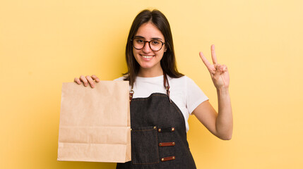 young hispanic woman smiling and looking friendly, showing number two. fast food deliver concept