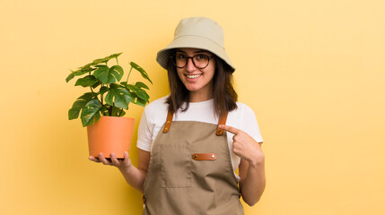 young hispanic woman feeling happy and pointing to self with an excited. gardener and plant concept