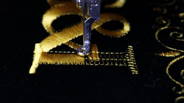 Machine embroidery on black velvet fabric with yellow thread. Embroidered ornaments and initials G and I. Close up. 4k video.