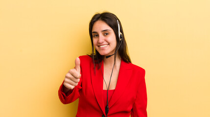 young hispanic woman feeling proud,smiling positively with thumbs up. telemarketer concept
