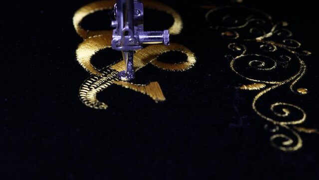 Machine embroidery on black velvet fabric with yellow thread. Embroidered ornaments and initials G and I. Close up. 4k video.